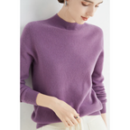 Femme portant un pull violet en cachemire, manches longues, col montant, avec un pantalon blanc. Mode élégante et confortable pour l'hiver.