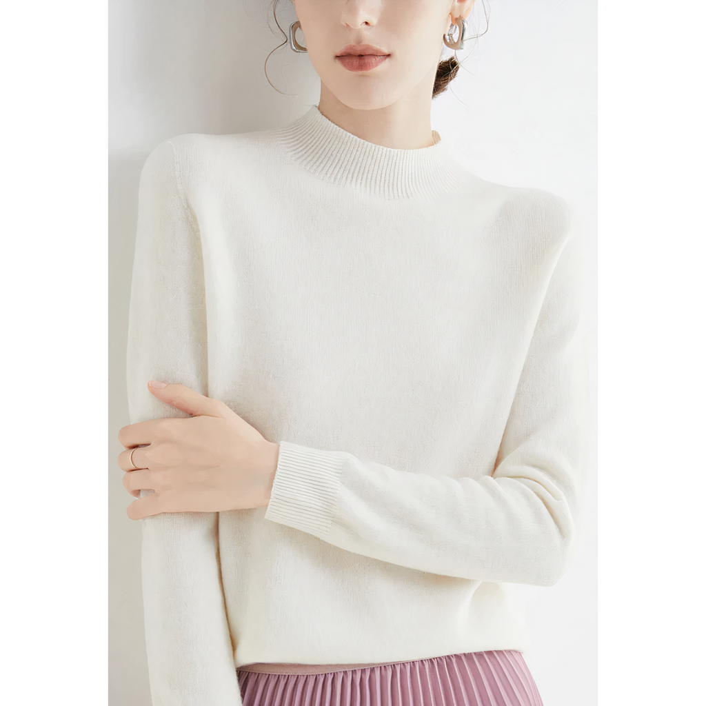 Femme portant un pull blanc en laine, manches longues, col montant, avec une jupe plissée rose. Mode élégante, tenue automne-hiver.