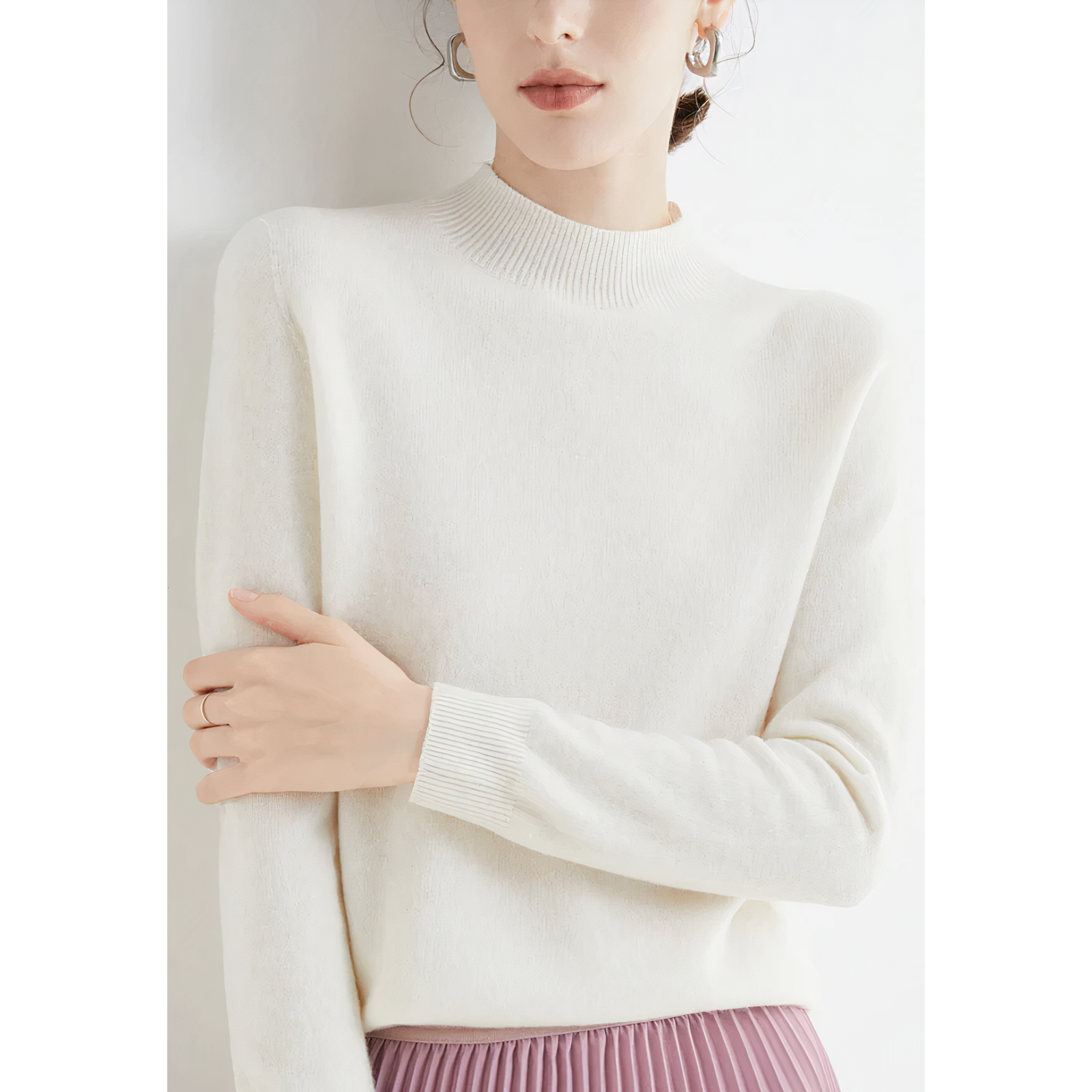 Femme portant un pull blanc en laine, manches longues, col montant, avec une jupe plissée rose. Mode élégante, tenue automne-hiver.