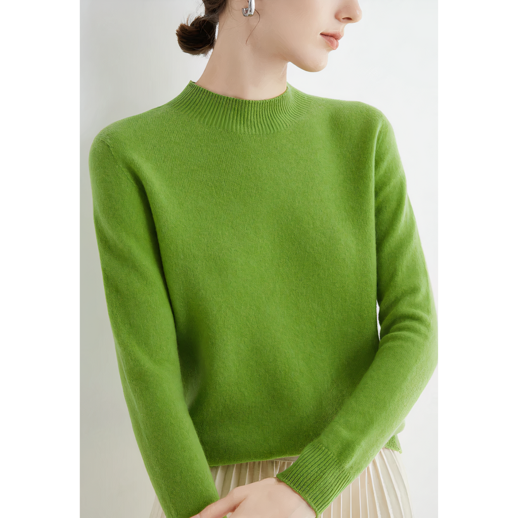 Femme portant un pull vert vif en laine, manches longues, col rond, avec jupe plissée beige. Mode élégante, tenue automne-hiver tendance.