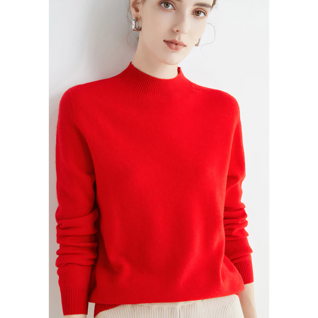 Femme portant un pull rouge vif, manches longues, col rond, posant contre un fond blanc. Mode féminine élégante, style automne-hiver.