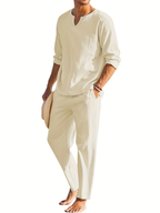 Homme en tenue décontractée beige, chemise à manches longues et pantalon assorti, tenant un chapeau. Mode masculine élégante et estivale.