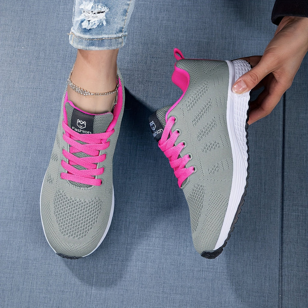 Baskets grises avec lacets roses, portées par une personne en jean déchiré, sur fond bleu. Chaussures de sport tendance pour femmes.