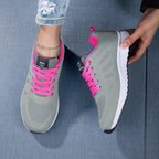 Baskets grises avec lacets roses, portées par une personne en jean déchiré, sur fond bleu. Chaussures de sport tendance pour femmes.