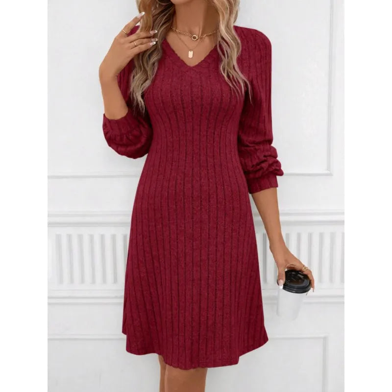 Robe pull rouge bordeaux à manches longues, col en V, femme tenant un gobelet. Mode automne-hiver, élégance décontractée, tendance féminine.