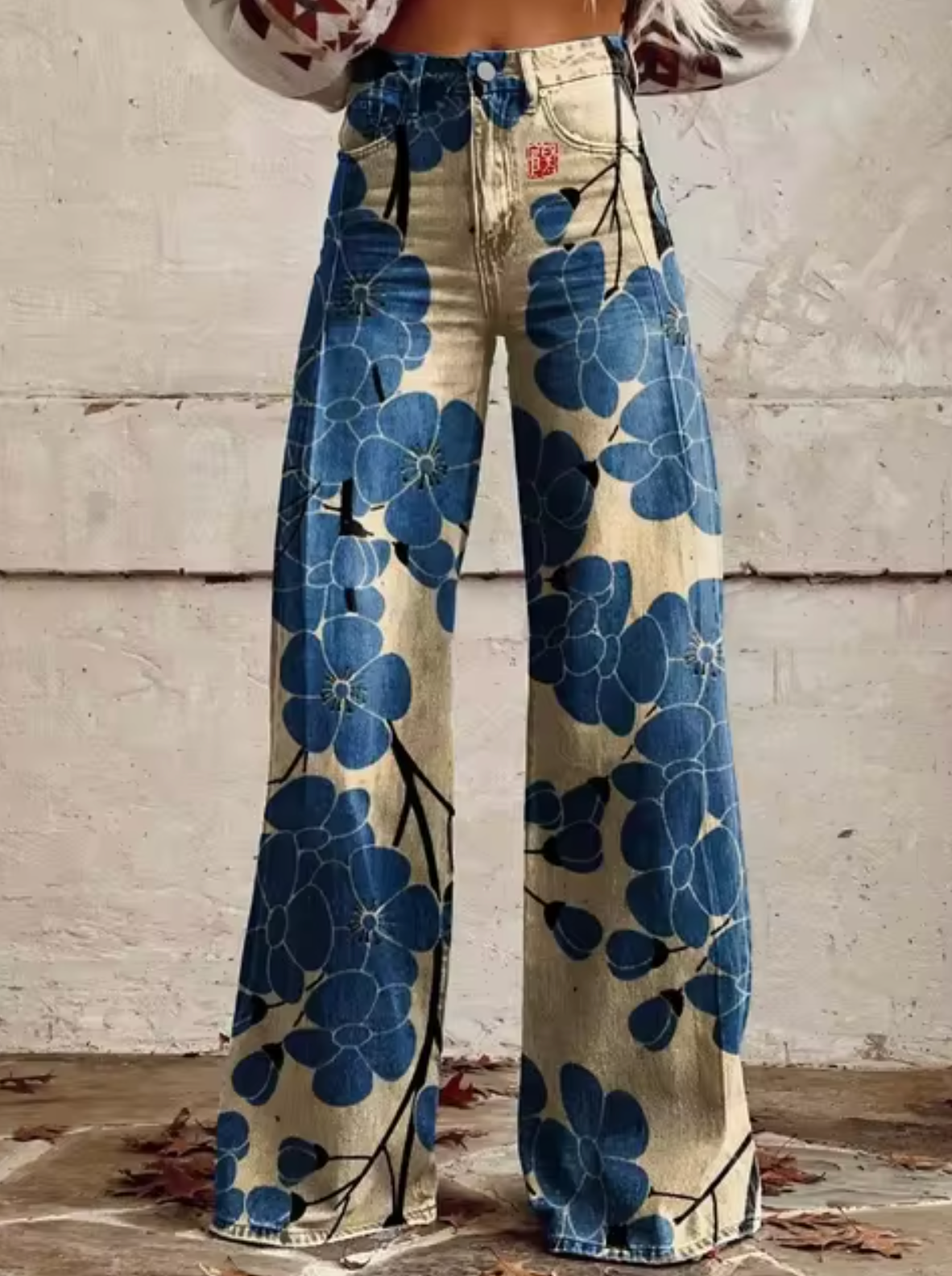 Pantalon en jean évasé à motifs floraux bleus, taille haute, style vintage. Mode femme, tendance rétro, imprimé floral audacieux.