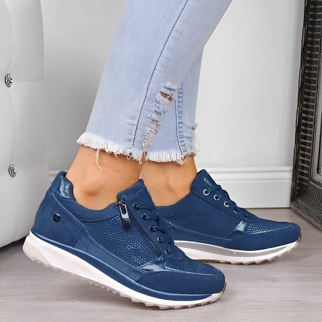 Jeans déchirés et baskets bleues élégantes pour femme, posées sur un sol en bois clair. Mode décontractée, chaussures tendance, style urbain.