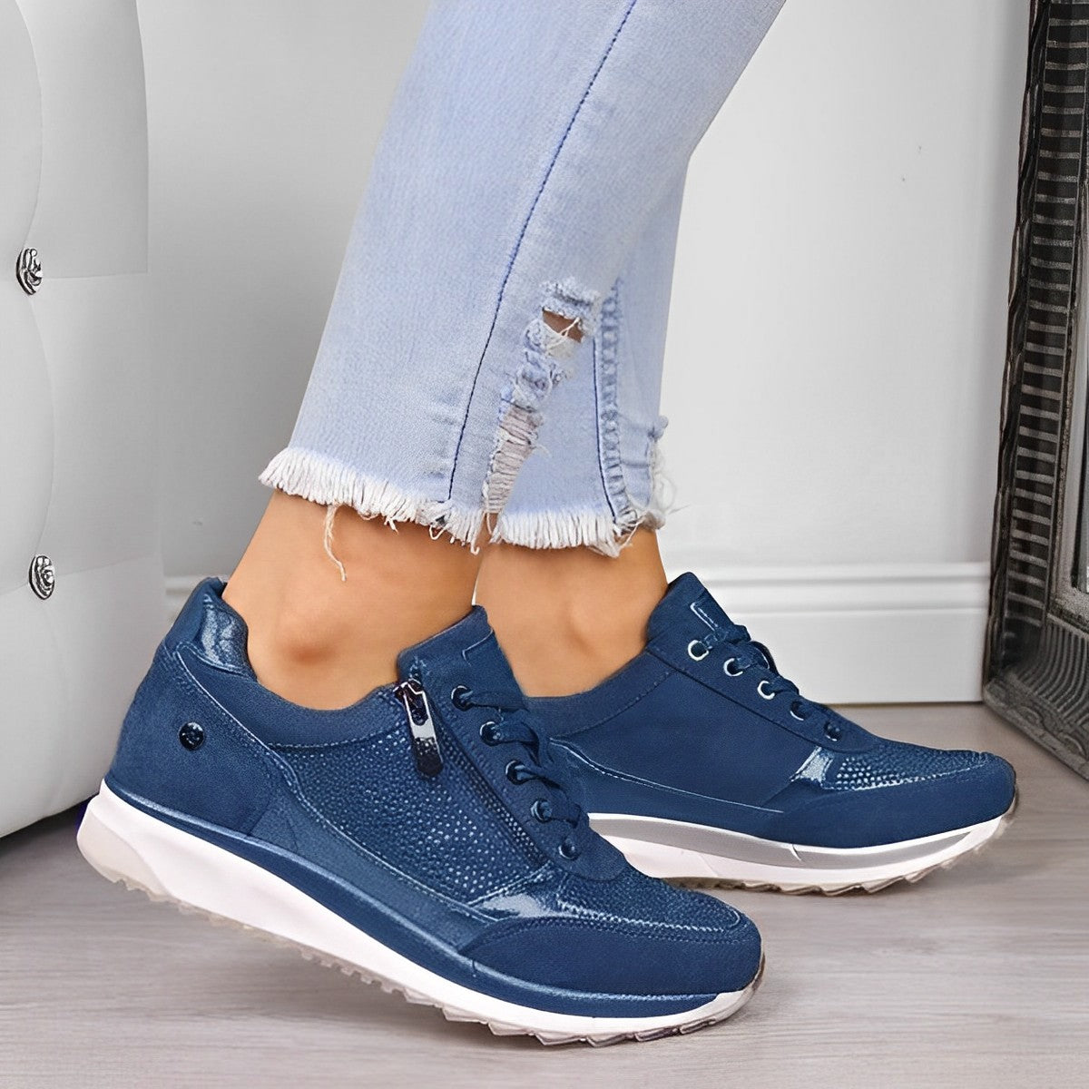 Jeans déchirés et baskets bleues élégantes pour femme, posées sur un sol en bois clair. Mode décontractée, chaussures tendance, style urbain.
