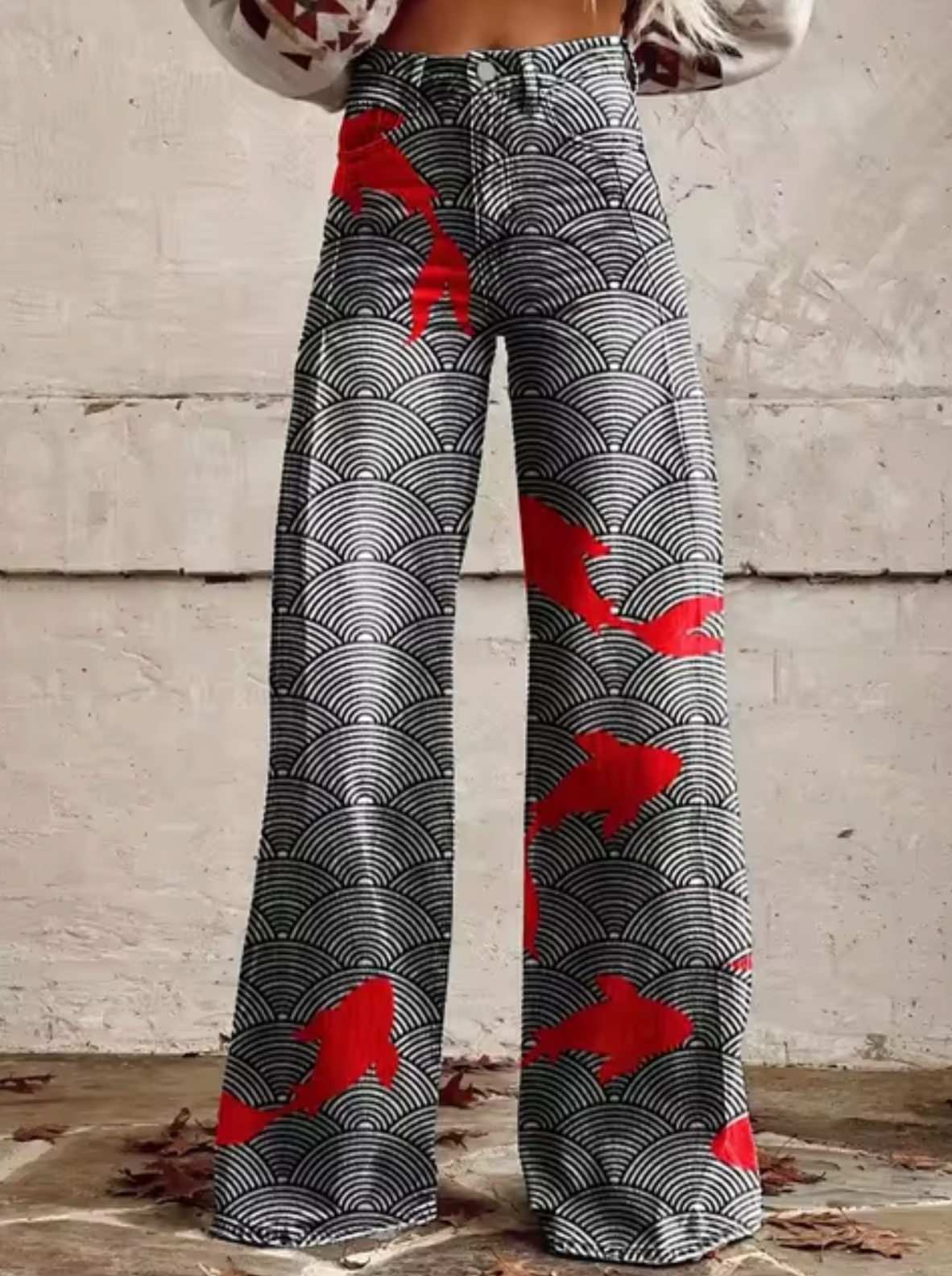Pantalon large à motifs géométriques noirs et blancs avec des accents rouges, style moderne et tendance, idéal pour la mode automne-hiver.