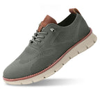 Chaussure de sport grise en maille respirante avec semelle blanche, lacets et détails marron. Idéale pour la course et le fitness.