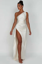 Robe longue blanche élégante à une épaule avec fente haute, portée par une femme. Mode soirée chic, style glamour, tendance 2023.