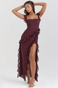 Femme portant une robe longue bordeaux à volants, posant élégamment. Mode féminine, robe de soirée chic, style glamour.