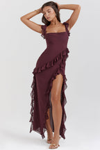 Femme portant une robe longue bordeaux à volants, posant élégamment. Mode féminine, robe de soirée chic, style glamour.