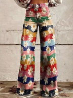 Pantalon évasé à motifs floraux multicolores, style vintage années 70, avec fleurs blanches et rayures colorées, mode rétro tendance.
