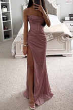 Robe de soirée rose scintillante avec fente haute, portée par une femme dans une chambre élégante. Mode glamour, tenue de soirée chic.