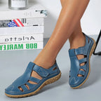 Sandales bleues en cuir pour femme avec semelle antidérapante, design ajouré, confortables et élégantes, posées sur fond de livres et décoration moderne.