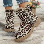 Bottes d'hiver à imprimé léopard avec doublure en fourrure, fermeture éclair latérale, semelle crantée, posées sur un sol en bois, fleurs en arrière-plan.