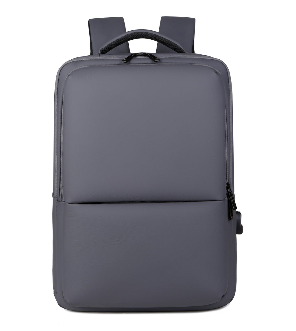 Sac à dos gris moderne et minimaliste, avec bretelles rembourrées, poche avant zippée, idéal pour ordinateur portable et usage quotidien.