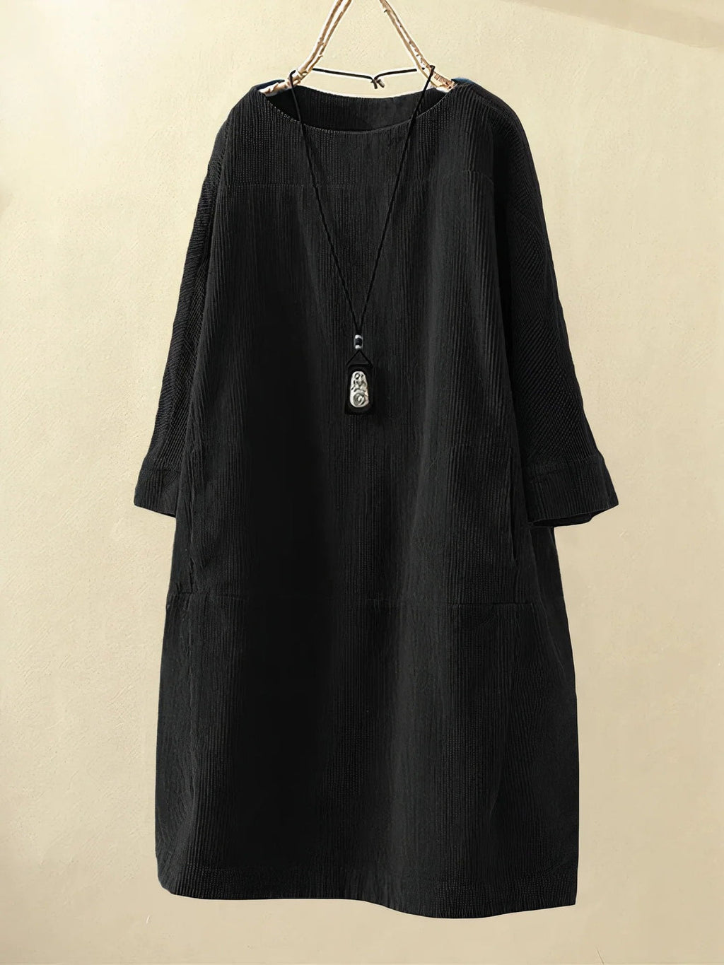 Robe noire en velours côtelé, manches longues, coupe ample, avec collier pendentif. Mode élégante, style décontracté, vêtement automne-hiver.