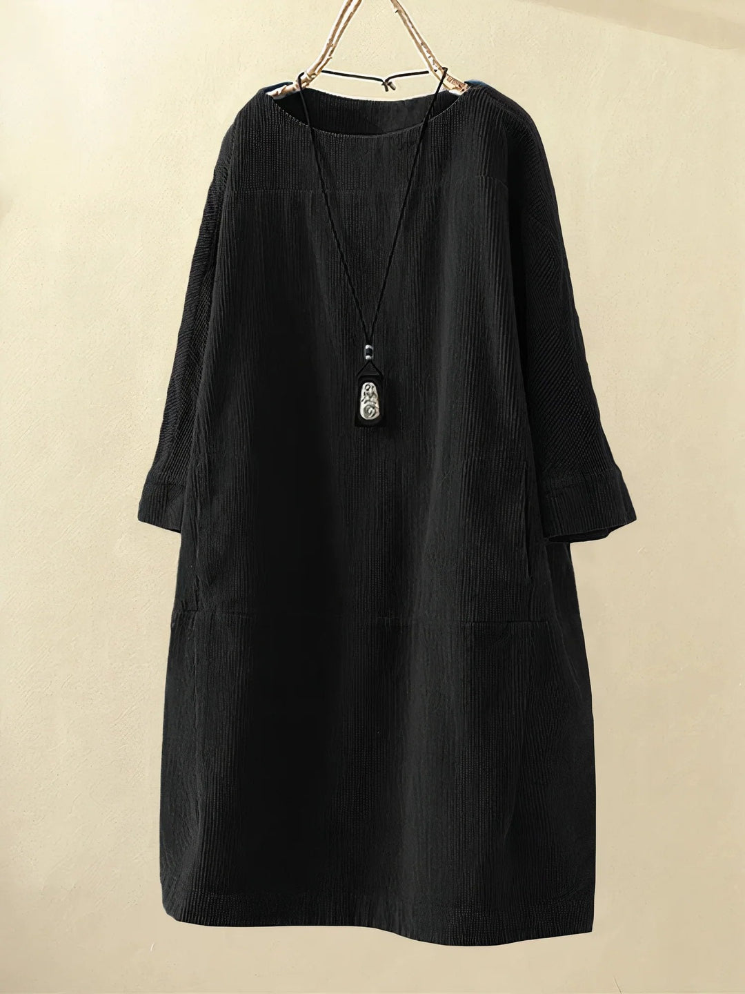 Robe noire en velours côtelé, manches longues, coupe ample, avec collier pendentif. Mode élégante, style décontracté, vêtement automne-hiver.