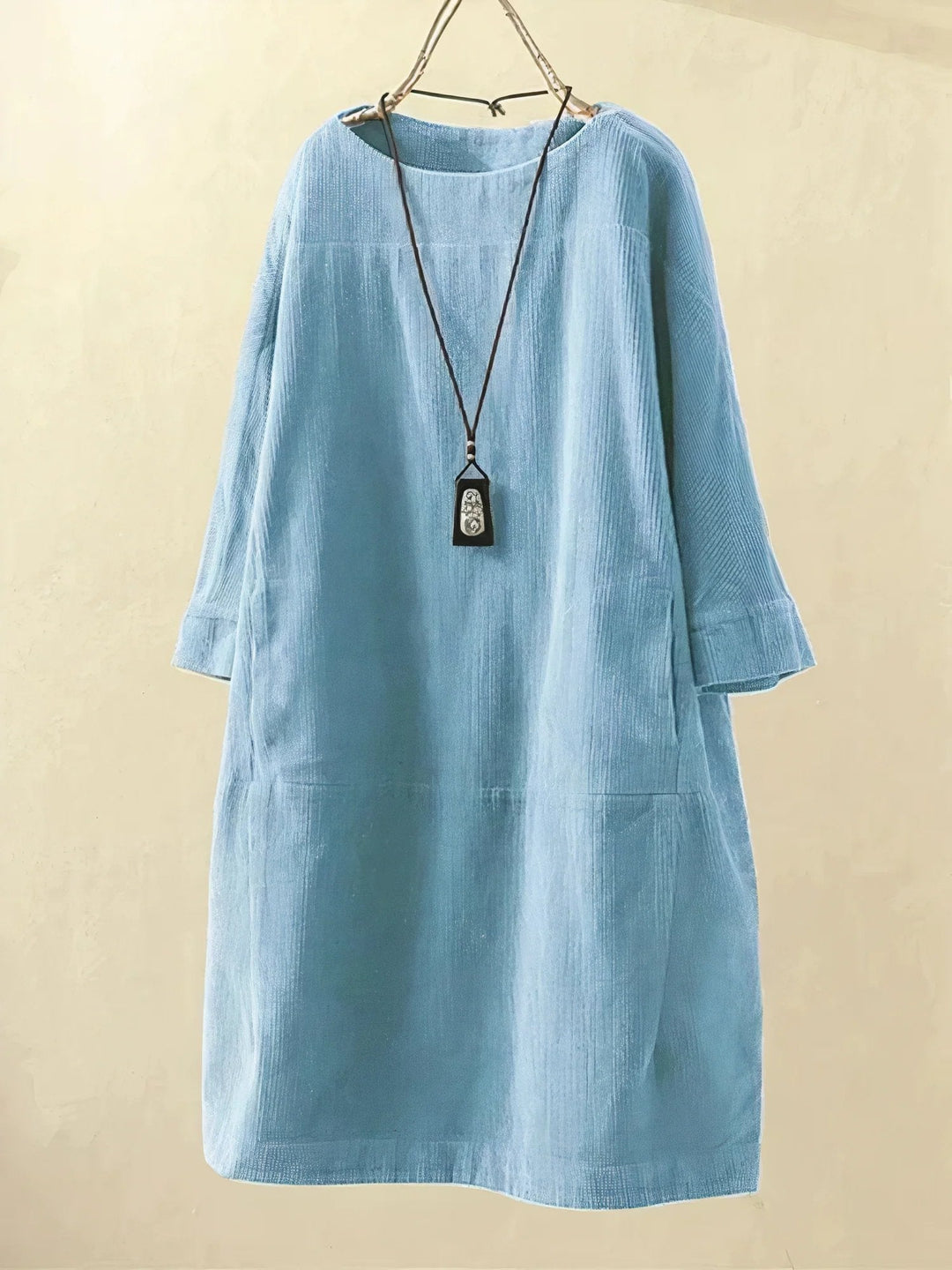 Robe en velours côtelé bleu clair, manches longues, coupe ample, col rond, suspendue sur un cintre. Mode féminine, style décontracté.