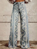 Jean évasé taille haute avec motif floral bleu sur fond beige, style vintage bohème, mode femme automne, devant mur texturé.