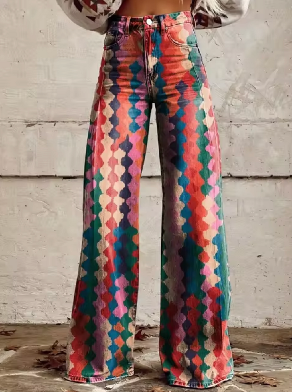 Pantalon évasé multicolore à motifs géométriques, style bohème, sur fond de mur en béton. Mode vintage, tendance années 70.
