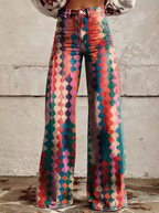 Pantalon évasé multicolore à motifs géométriques, style bohème, sur fond de mur en béton. Mode vintage, tendance années 70.