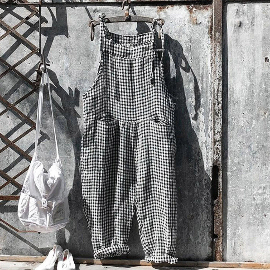 Salopette à carreaux noir et blanc suspendue sur un mur en métal rouillé, sac blanc à côté. Mode vintage, style rétro, vêtements décontractés.