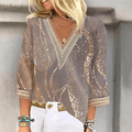 Blouse élégante à motifs dorés et argentés, manches trois-quarts, col en V, portée par une femme blonde. Mode féminine chic et tendance.