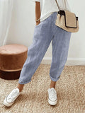 Pantalon rayé bleu et blanc, style décontracté, porté avec un t-shirt blanc, baskets blanches et sac en osier. Mode estivale tendance.
