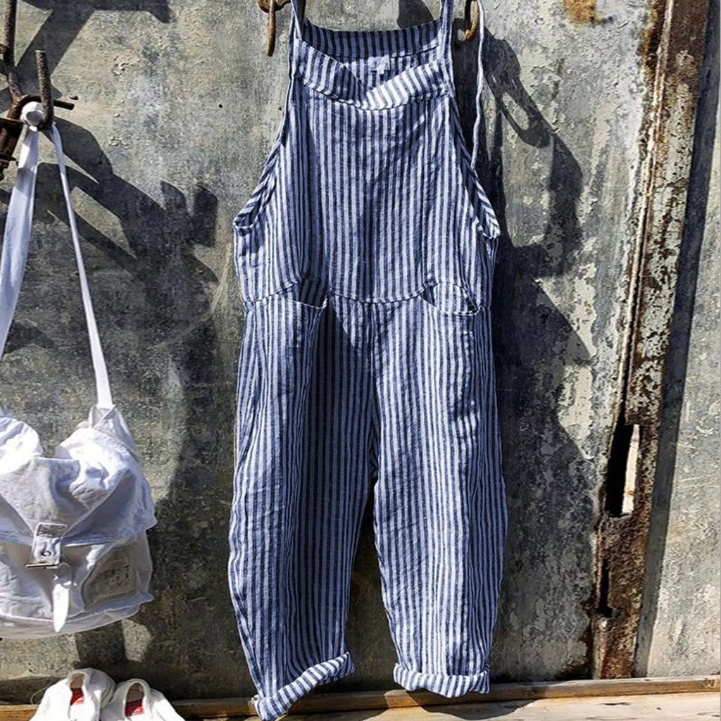 Salopette rayée bleue et blanche suspendue sur un mur en métal vieilli, style vintage, mode décontractée, tendance estivale, vêtements en lin.