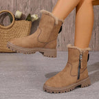 Bottes en daim marron avec doublure en fourrure, fermeture éclair latérale, semelles crantées. Sac en osier et fleurs blanches en arrière-plan.