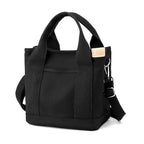 Sac à main noir en toile avec bandoulière réglable et poignées robustes, design moderne et pratique, idéal pour le quotidien et le shopping.