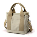 Sac à main en toile beige avec bandoulière réglable et poignées robustes. Design minimaliste, idéal pour un usage quotidien et tendance.