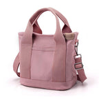 Sac à main rose en toile avec bandoulière réglable, poignées robustes et poche avant. Accessoire mode tendance pour femme.