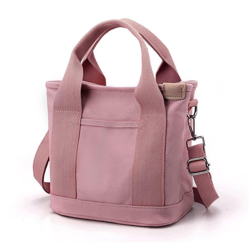Sac à main rose en toile avec bandoulière réglable, poignées robustes et poche avant. Accessoire mode tendance pour femme.