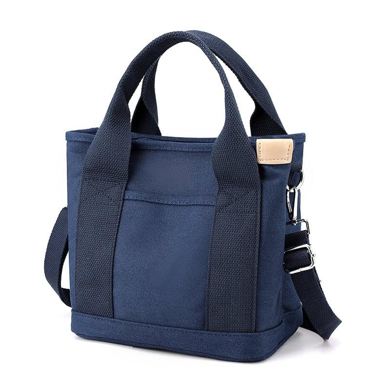 Sac fourre-tout en toile bleu marine avec poignées robustes et bandoulière ajustable. Design moderne, idéal pour le quotidien et le voyage.