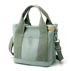 Sac fourre-tout vert en toile avec bandoulière réglable, poignées robustes et poche avant. Idéal pour le shopping et les sorties décontractées.