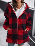 Femme portant un manteau à carreaux rouges et noirs en laine bouclée, capuche, poches, style décontracté, mode automne-hiver.