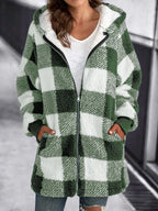 Veste à carreaux verts et blancs en laine bouclée, fermée par une fermeture éclair, portée par une femme. Mode automne-hiver, style décontracté.