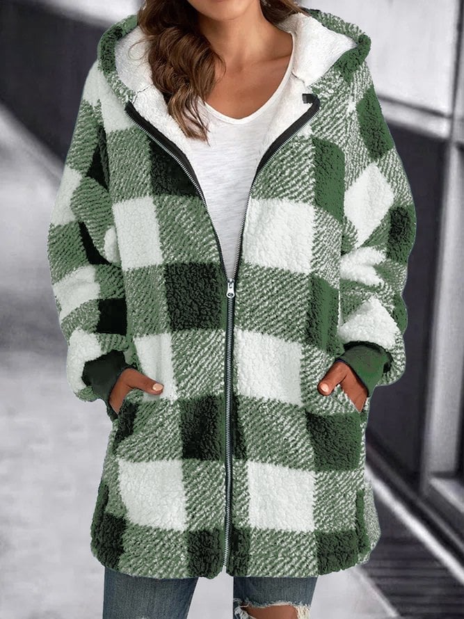 Veste à carreaux verts et blancs en laine bouclée, fermée par une fermeture éclair, portée par une femme. Mode automne-hiver, style décontracté.