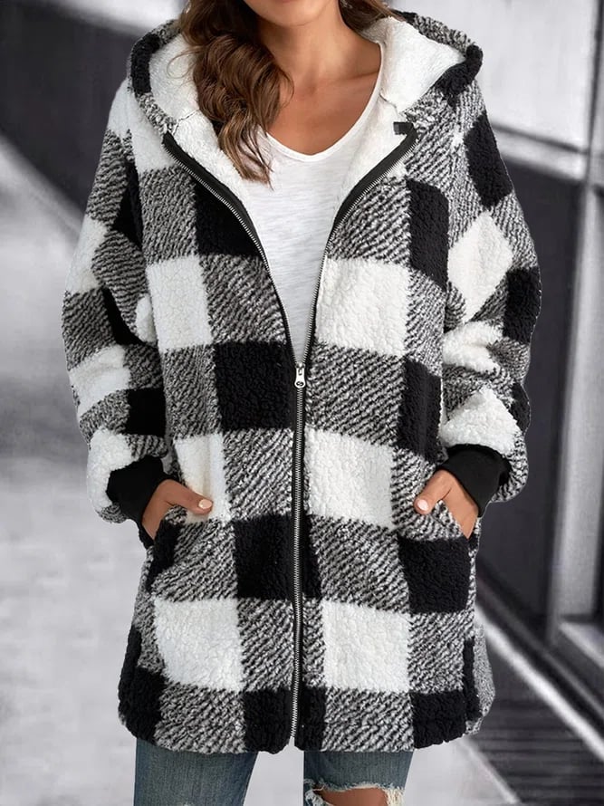 Veste à carreaux noir et blanc en laine bouclée, fermeture éclair, poches avant, portée par une femme en jean, style décontracté et tendance.