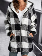 Veste à carreaux noir et blanc en laine bouclée, fermeture éclair, poches avant, portée par une femme en jean, style décontracté et tendance.