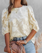 Femme portant un chemisier en dentelle blanche à manches bouffantes, associée à un jean bleu et un sac à main beige, mode élégante et tendance.