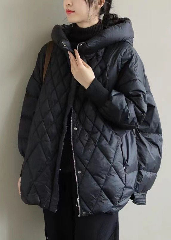 Femme portant une doudoune noire matelassée avec capuche, style hiver, mode féminine, vêtement chaud, tendance automne-hiver, look décontracté.