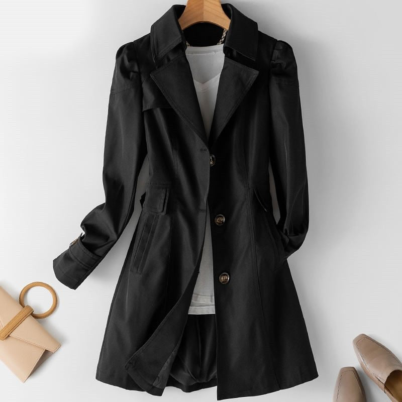 Manteau noir élégant pour femme sur cintre, avec col à revers et boutons, accompagné d'un sac à main beige et de chaussures à talons.