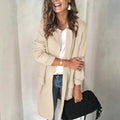 Femme souriante portant un manteau beige élégant, chemise blanche, jeans, tenant un sac noir. Mode automne chic, style décontracté tendance.