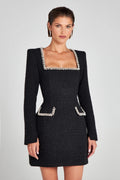 Robe noire élégante en tweed avec col carré et bordures perlées, manches longues, poches décoratives, portée par une femme. Mode chic et sophistiquée.