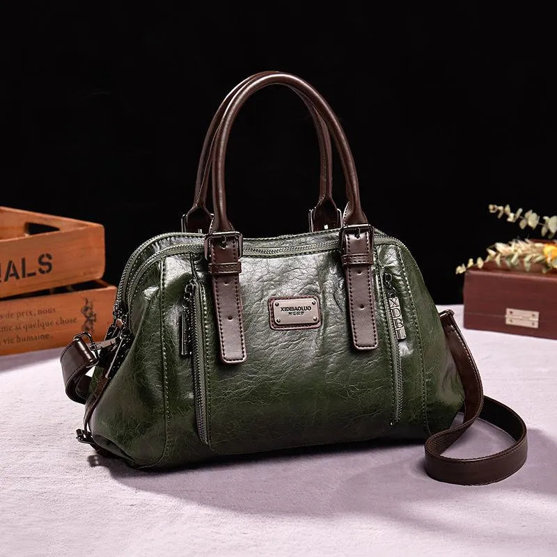 Sac à main en cuir vert foncé avec poignées marron, design élégant, étiquette métallique, posé sur une table blanche, fond noir. Accessoire mode tendance.